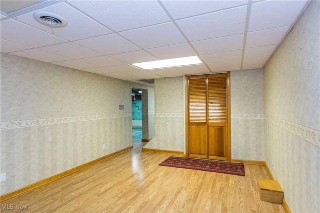 empty room with hardwood / wood-style floors and a drop ceiling