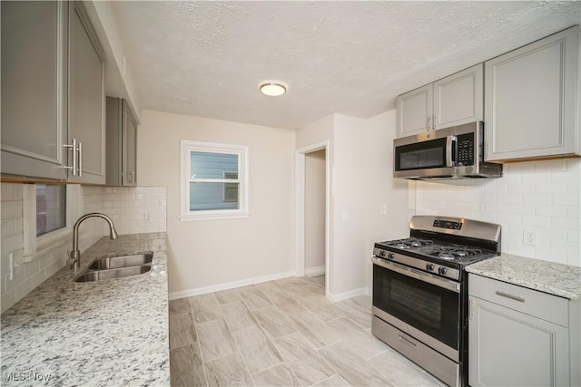 kitchen featuring decorative backsplash, gray cabinetry, a textured ceiling, stainless steel appliances, and sink