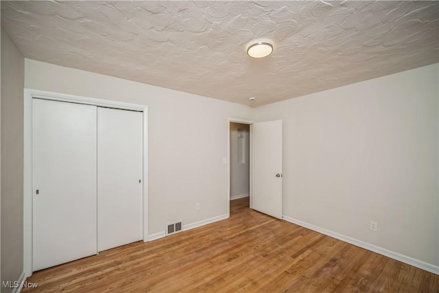 unfurnished bedroom with hardwood / wood-style floors, a textured ceiling, and a closet