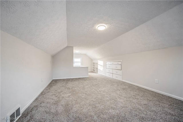 bonus room with vaulted ceiling, carpet floors, and a textured ceiling