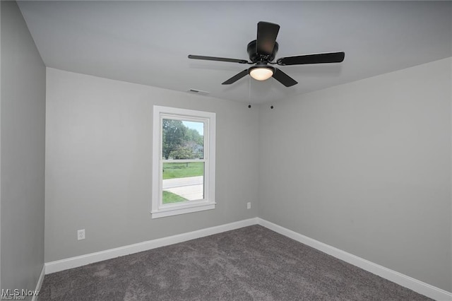 empty room featuring ceiling fan and dark colored carpet