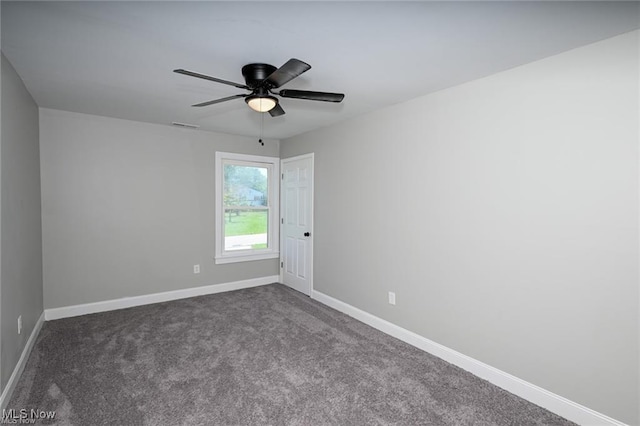 spare room featuring ceiling fan and dark carpet