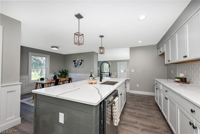 kitchen featuring pendant lighting, dark wood-type flooring, white cabinets, sink, and an island with sink