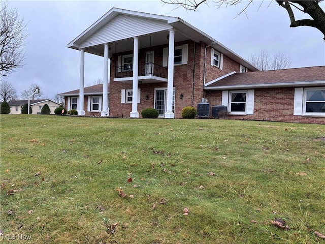 view of front of home with a front yard, a balcony, and central air condition unit