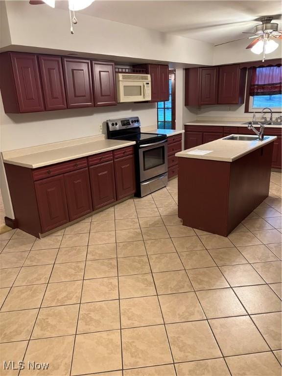 kitchen featuring ceiling fan, sink, a center island, stainless steel range with electric stovetop, and light tile patterned flooring