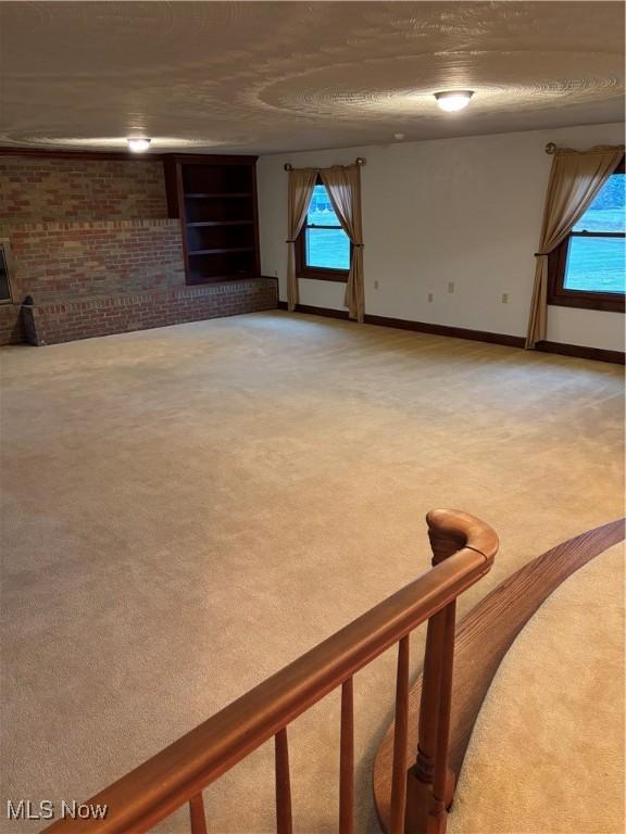 interior space with a fireplace, carpet, and brick wall