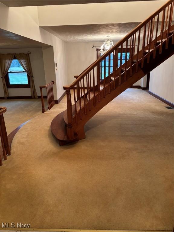 staircase featuring carpet floors and a notable chandelier