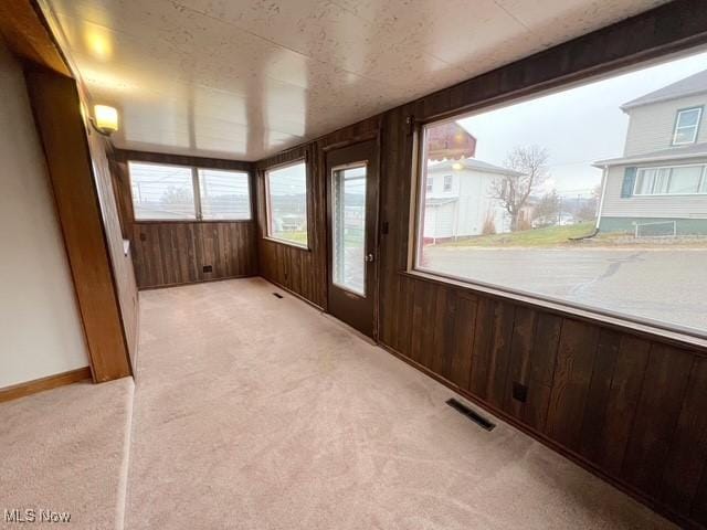 unfurnished sunroom featuring beam ceiling