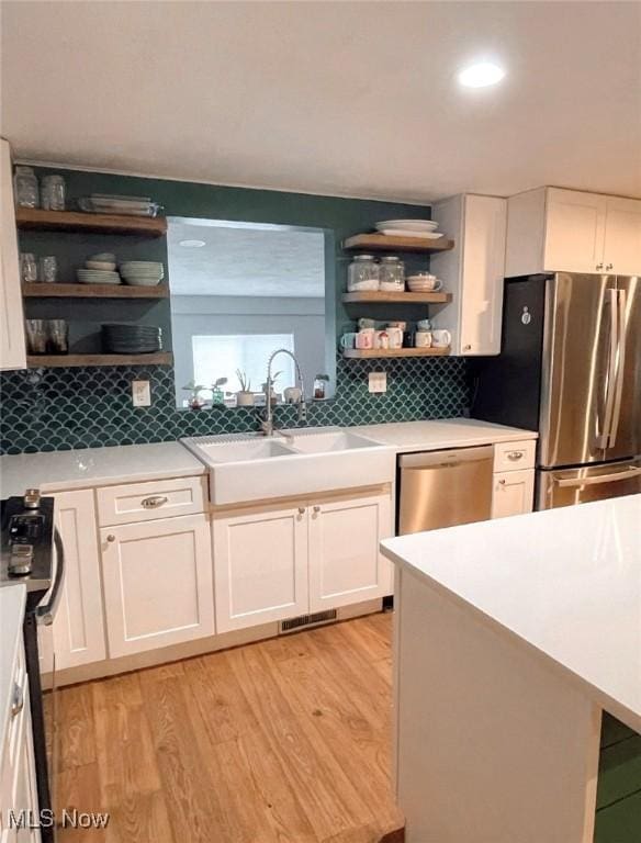 kitchen featuring light hardwood / wood-style flooring, white cabinetry, sink, and stainless steel appliances