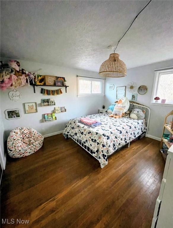 bedroom featuring dark hardwood / wood-style flooring, a textured ceiling, and multiple windows