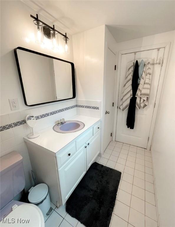 bathroom featuring tile patterned floors, vanity, toilet, and tile walls