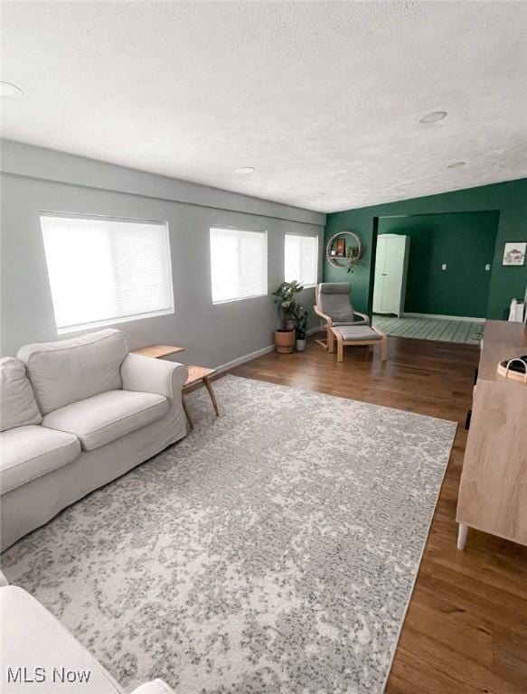 living room with a textured ceiling and dark wood-type flooring