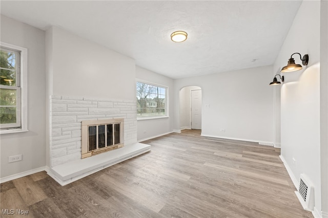 unfurnished living room with a fireplace, plenty of natural light, and light wood-type flooring