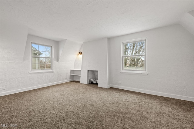 interior space featuring carpet, a fireplace, a textured ceiling, and vaulted ceiling