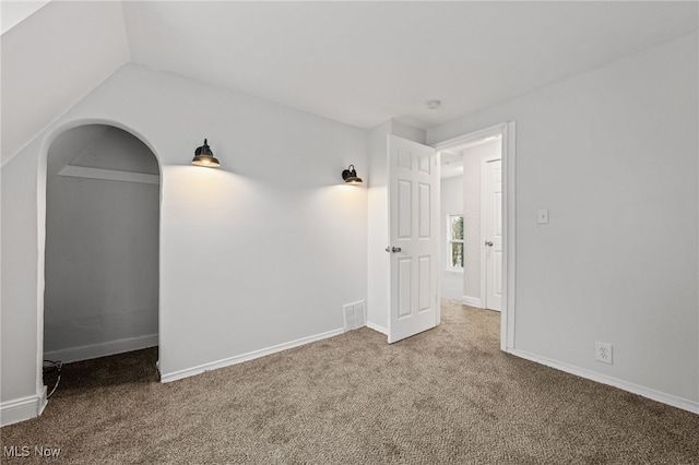 empty room featuring carpet flooring and vaulted ceiling