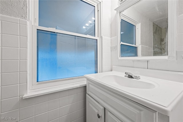 bathroom featuring vanity and tile walls