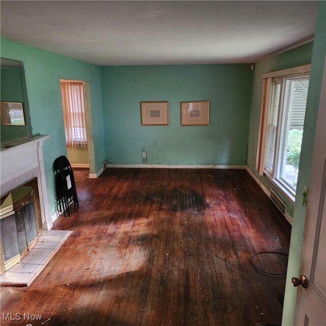 unfurnished living room with a tiled fireplace and hardwood / wood-style flooring