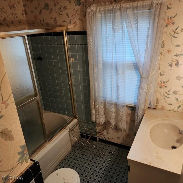 full bathroom featuring combined bath / shower with glass door, vanity, and toilet