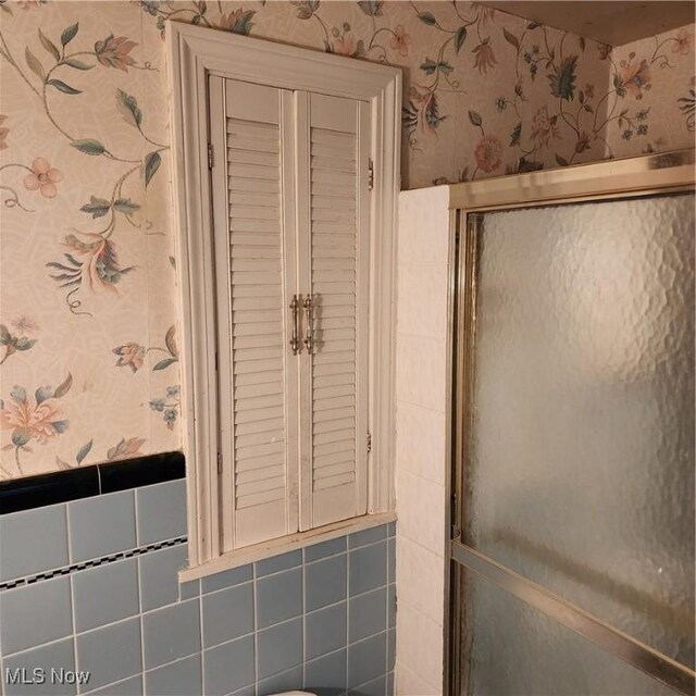 bathroom featuring a shower with door and tile walls