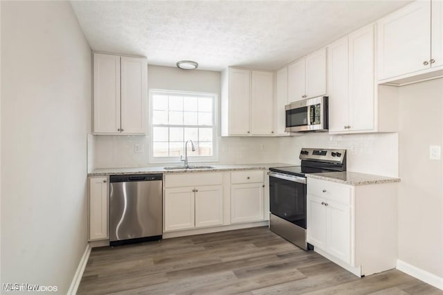 kitchen with light hardwood / wood-style flooring, stainless steel appliances, white cabinetry, and sink