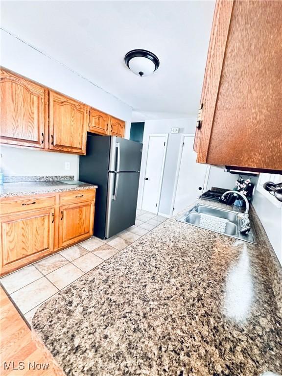 kitchen featuring light tile patterned floors, a sink, and freestanding refrigerator