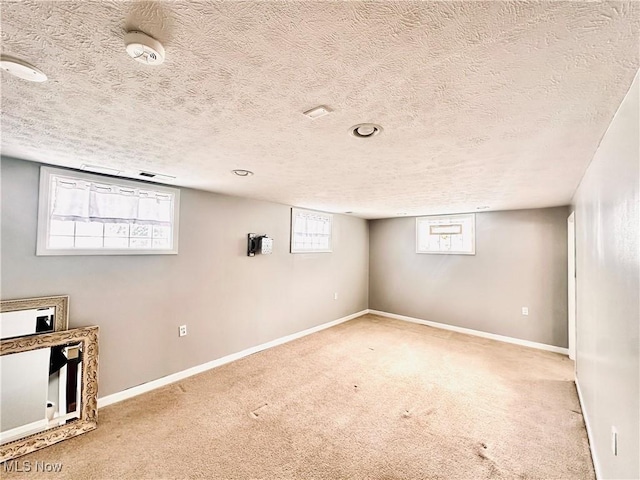 basement with carpet floors, baseboards, and a textured ceiling