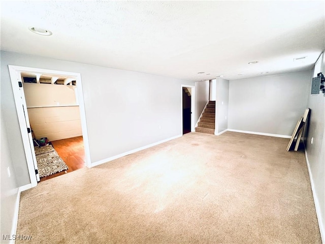 unfurnished room with carpet, stairs, and baseboards