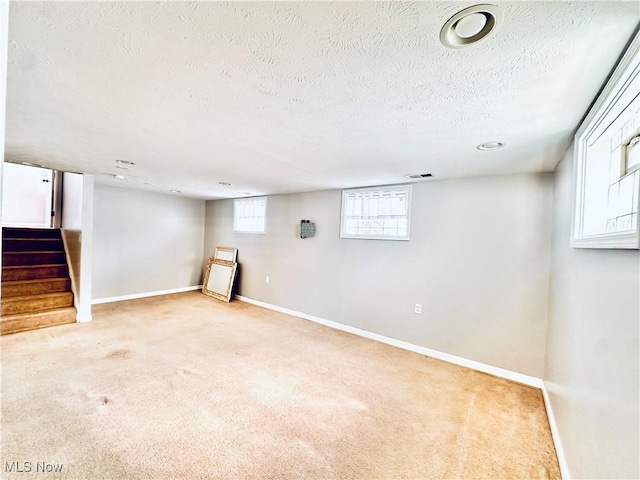 below grade area with carpet, stairway, baseboards, and a textured ceiling