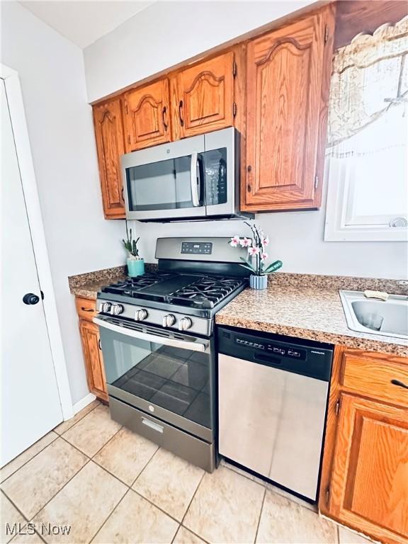 kitchen with appliances with stainless steel finishes, brown cabinetry, and a sink