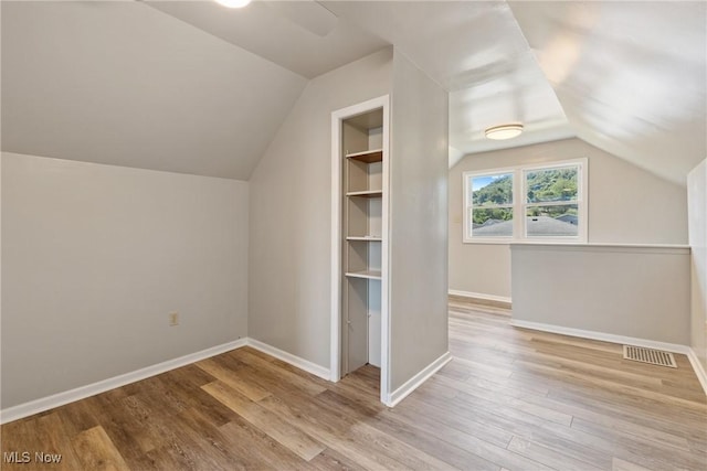 additional living space featuring vaulted ceiling, light hardwood / wood-style flooring, and built in features