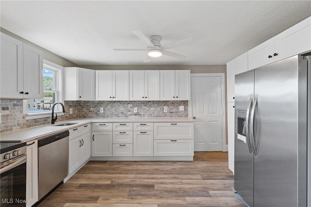 kitchen featuring sink, ceiling fan, light wood-type flooring, appliances with stainless steel finishes, and white cabinetry