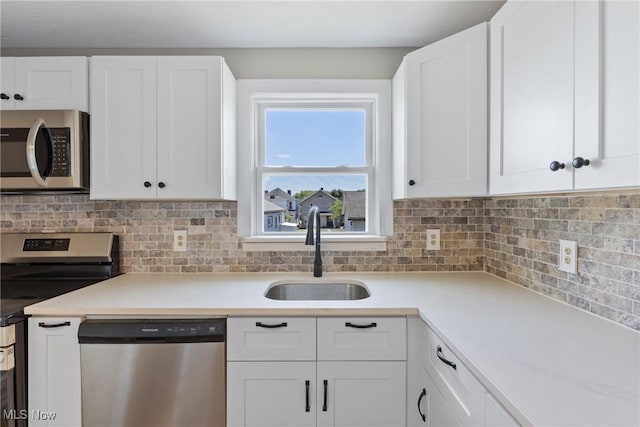 kitchen with white cabinets, appliances with stainless steel finishes, tasteful backsplash, and sink