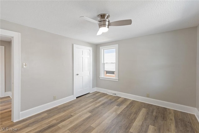 spare room featuring a textured ceiling, hardwood / wood-style flooring, and ceiling fan