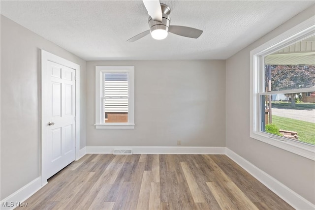 spare room with ceiling fan, a textured ceiling, and light wood-type flooring