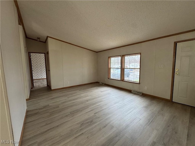 unfurnished room with crown molding, a textured ceiling, and light wood-type flooring