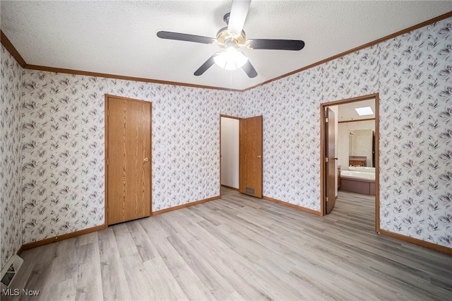 unfurnished bedroom with connected bathroom, crown molding, light hardwood / wood-style flooring, and a textured ceiling