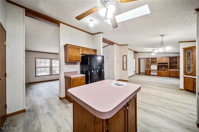 kitchen with crown molding, black fridge, pendant lighting, and a skylight