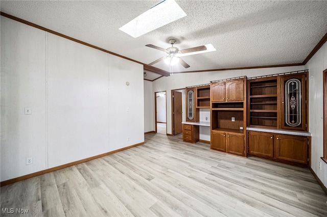 unfurnished living room featuring lofted ceiling with skylight, light wood-type flooring, ornamental molding, ceiling fan, and a textured ceiling