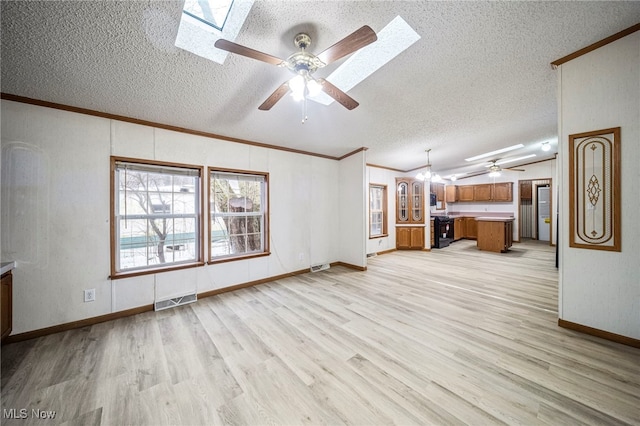 unfurnished living room with a textured ceiling, light wood-type flooring, ornamental molding, vaulted ceiling with skylight, and ceiling fan with notable chandelier