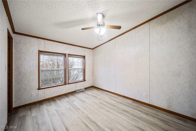 empty room featuring ornamental molding, a textured ceiling, and light wood-type flooring