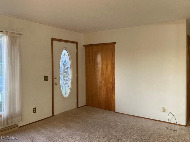 carpeted foyer with baseboard heating and a healthy amount of sunlight