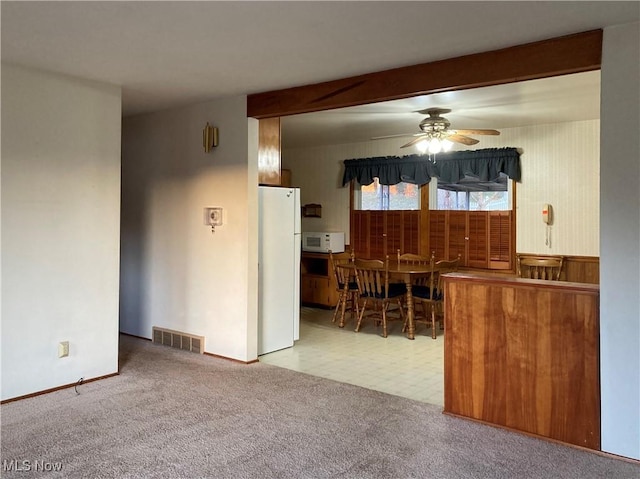 kitchen featuring beamed ceiling, ceiling fan, white appliances, and light carpet