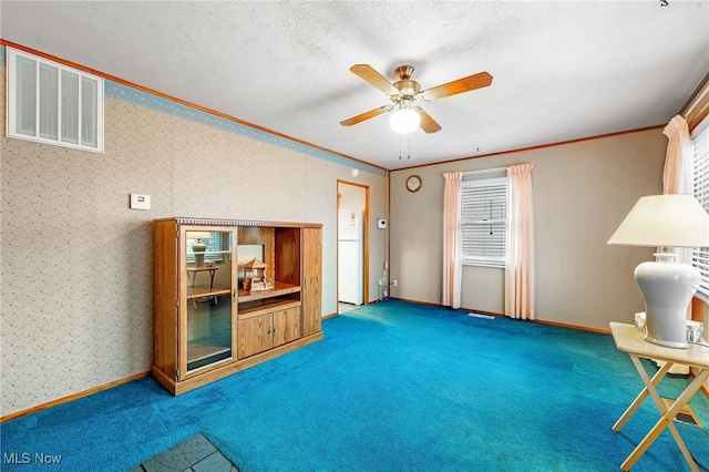 living area featuring a textured ceiling, carpet floors, ceiling fan, and ornamental molding