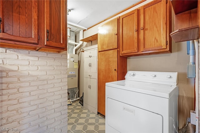 washroom with cabinets, washer / clothes dryer, and brick wall