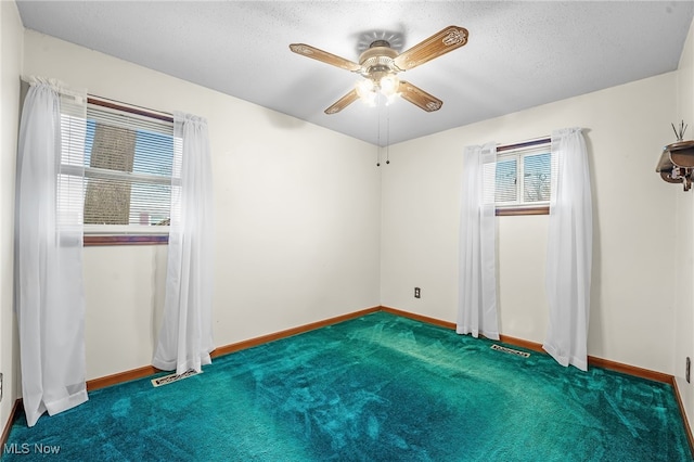 carpeted spare room with a textured ceiling, a wealth of natural light, and ceiling fan