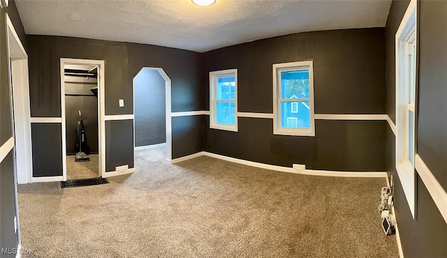 unfurnished room with carpet flooring and a textured ceiling