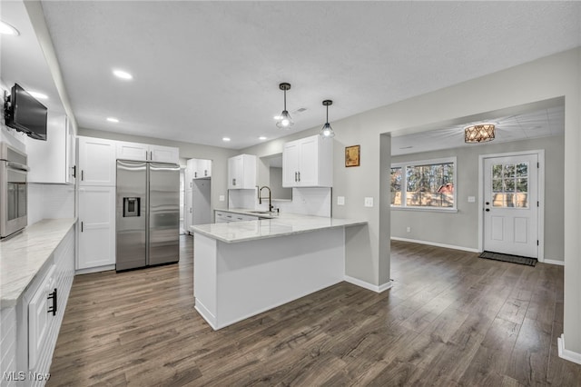 kitchen with kitchen peninsula, stainless steel appliances, sink, white cabinets, and dark hardwood / wood-style floors