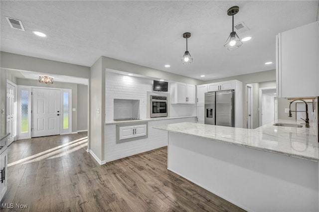 kitchen featuring white cabinets, sink, kitchen peninsula, wood-type flooring, and stainless steel appliances