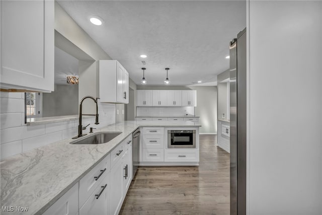 kitchen featuring white cabinets, light hardwood / wood-style flooring, light stone countertops, and sink