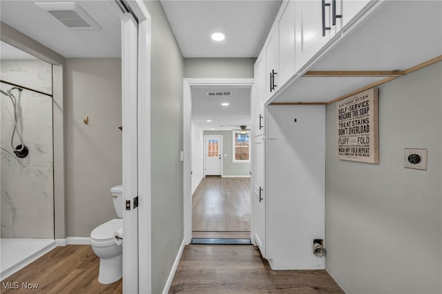 bathroom featuring toilet, ceiling fan, hardwood / wood-style floors, and walk in shower